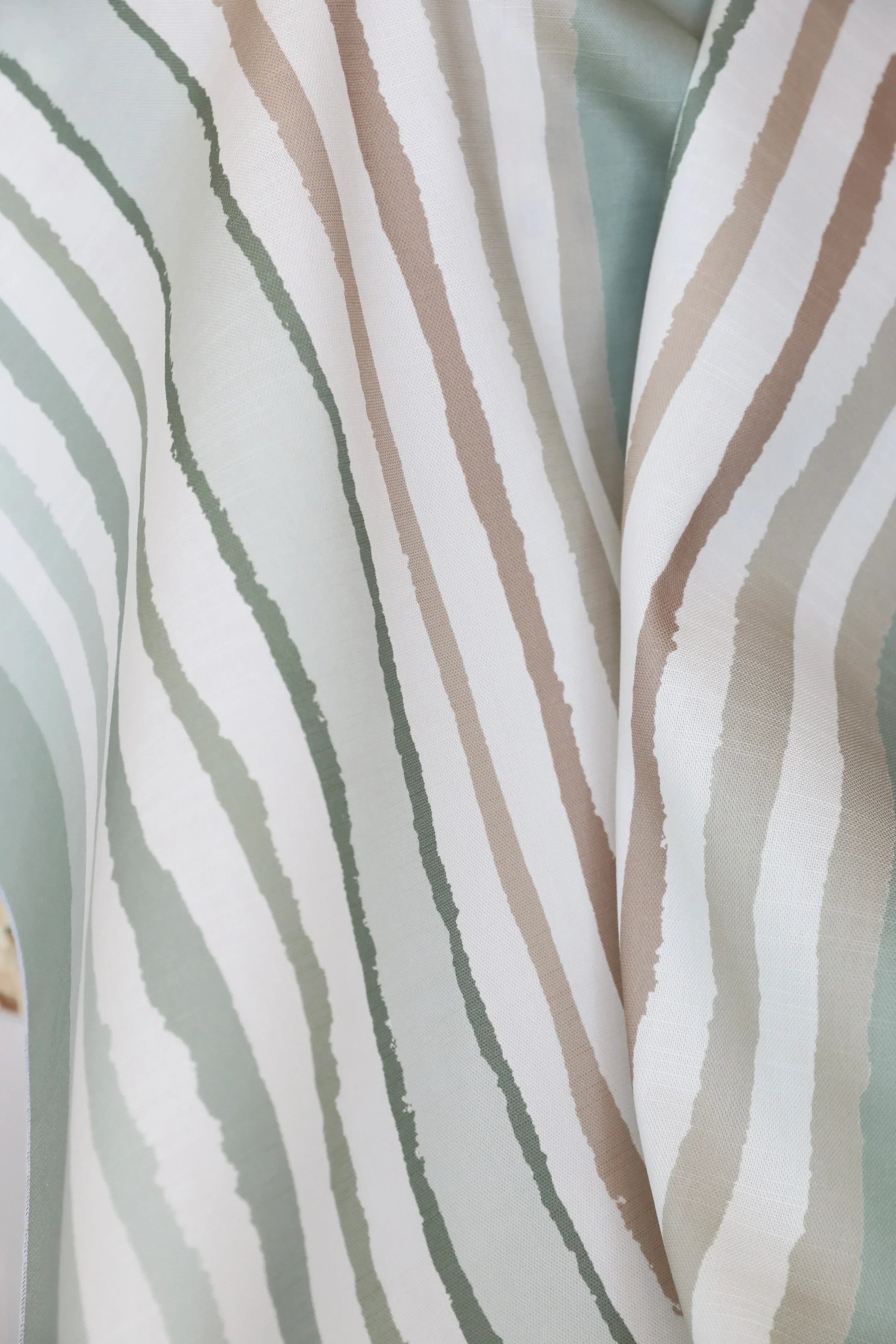 Close-up of striped luxury fabric with horizontal lines in beige, green, and white.